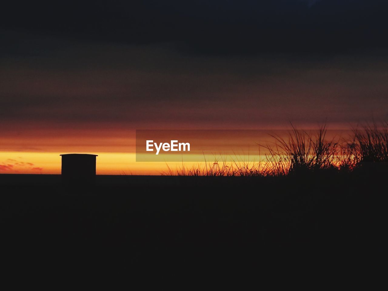 Scenic view of silhouette landscape against cloudy sky during sunset