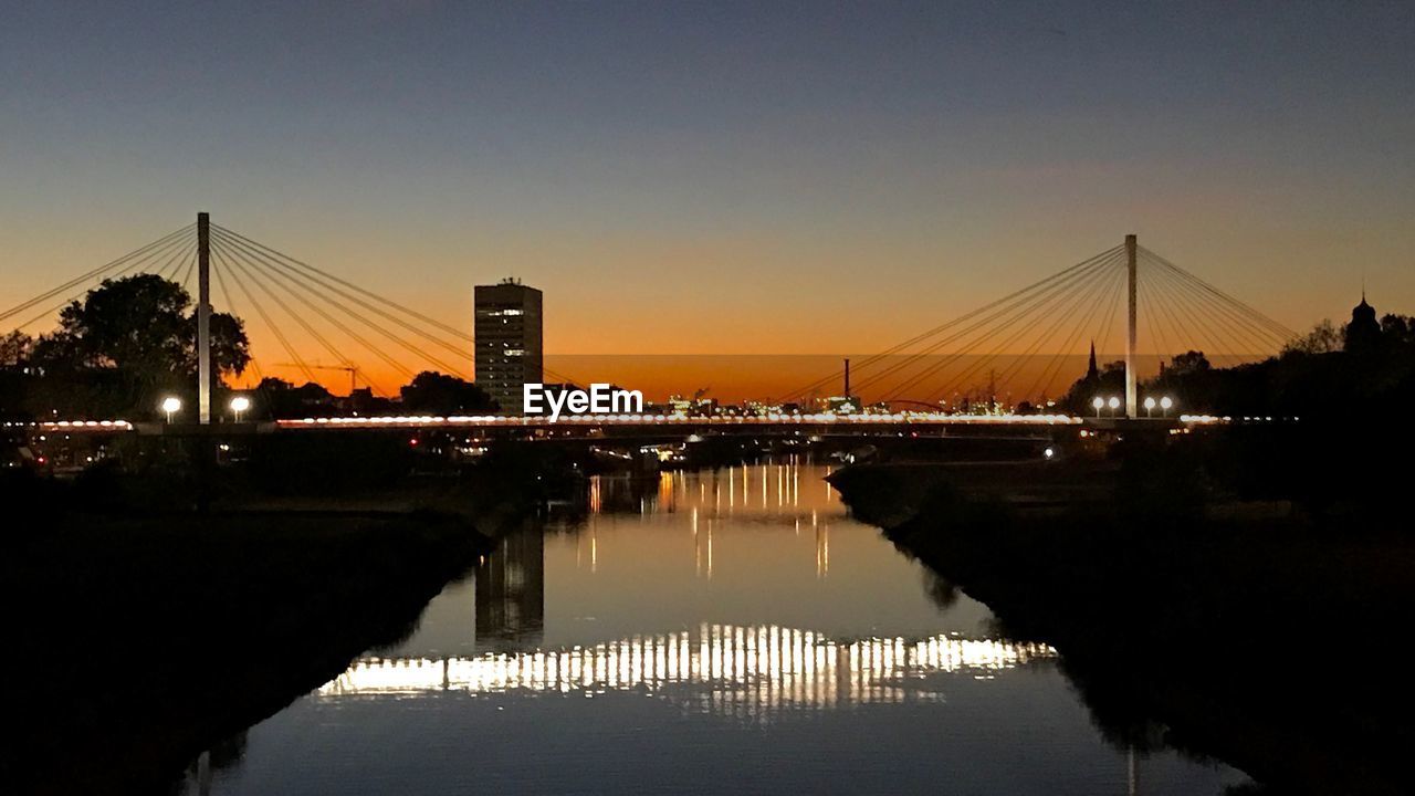 BRIDGE OVER RIVER AGAINST SKY AT SUNSET