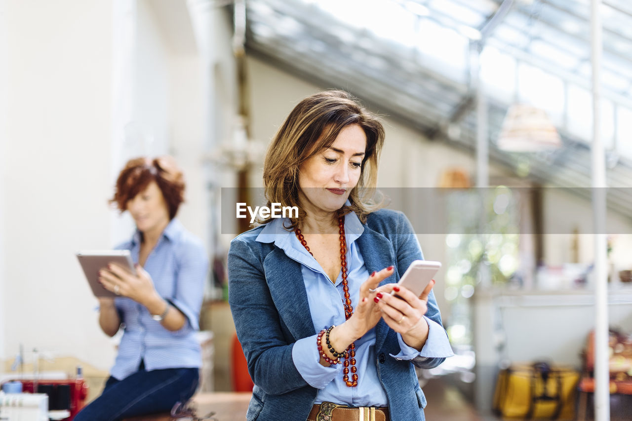 Contemporary mature businesswoman texting on mobile phone