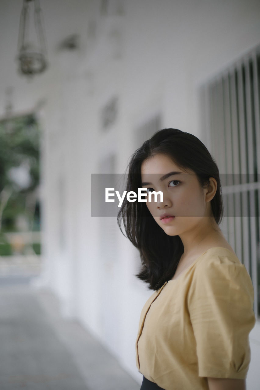 Portrait of young woman standing in corridor