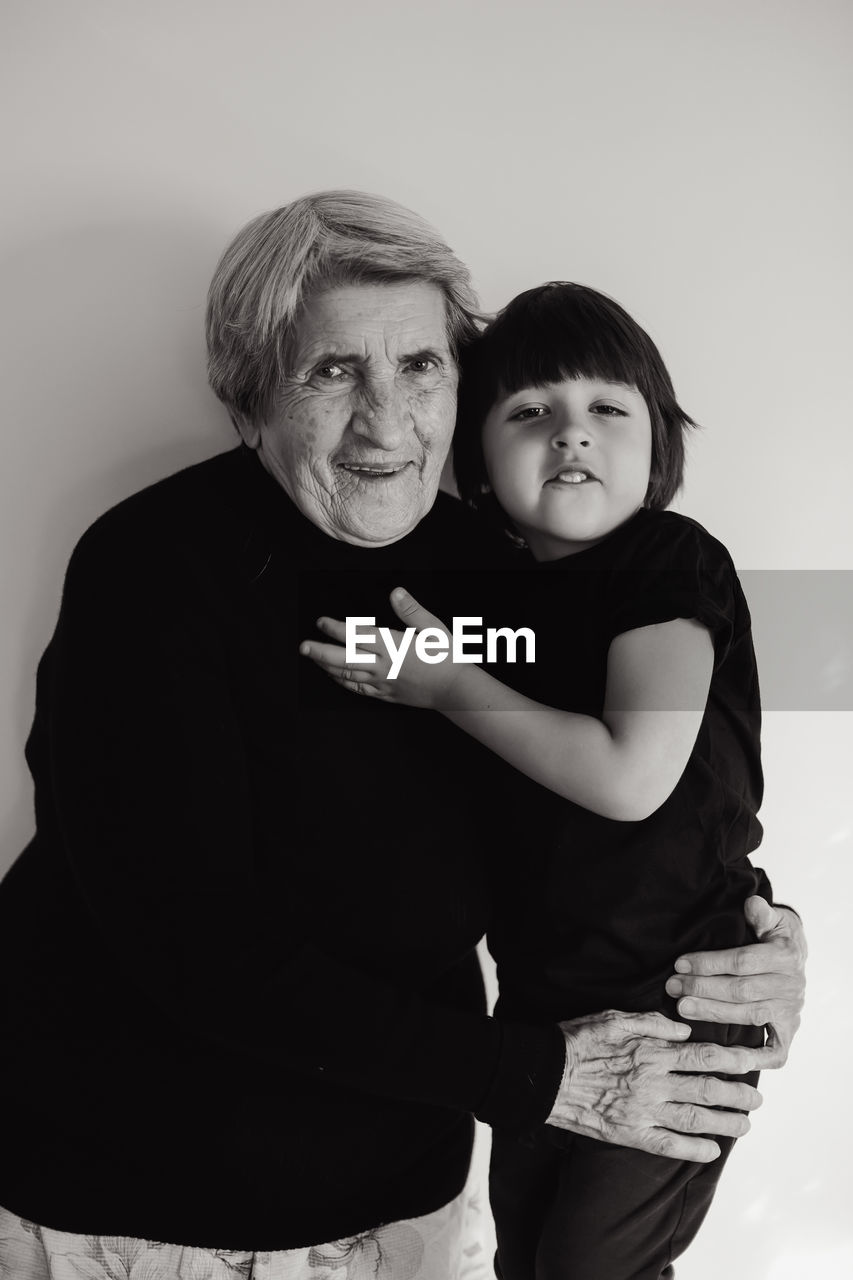 Funny grandson in a black t-shirt stands next to an old grandmother