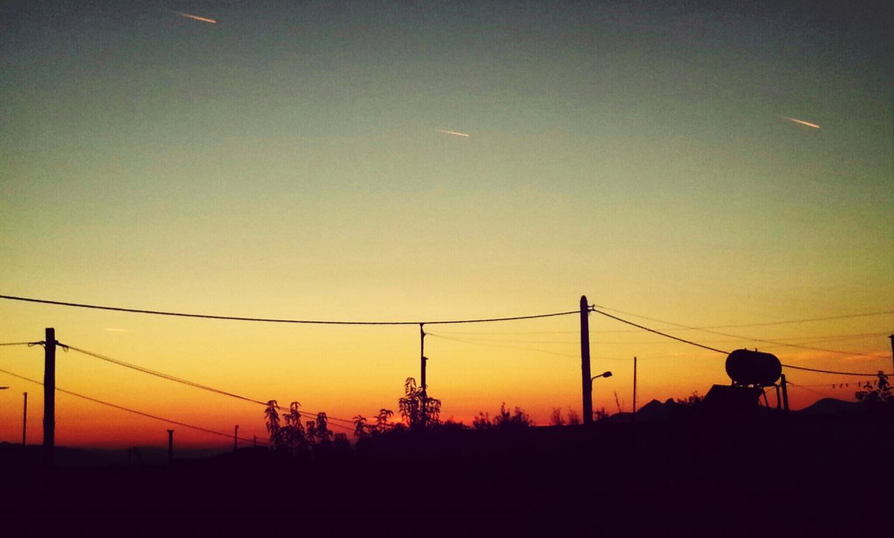 SILHOUETTE OF ELECTRICITY PYLONS ON LANDSCAPE