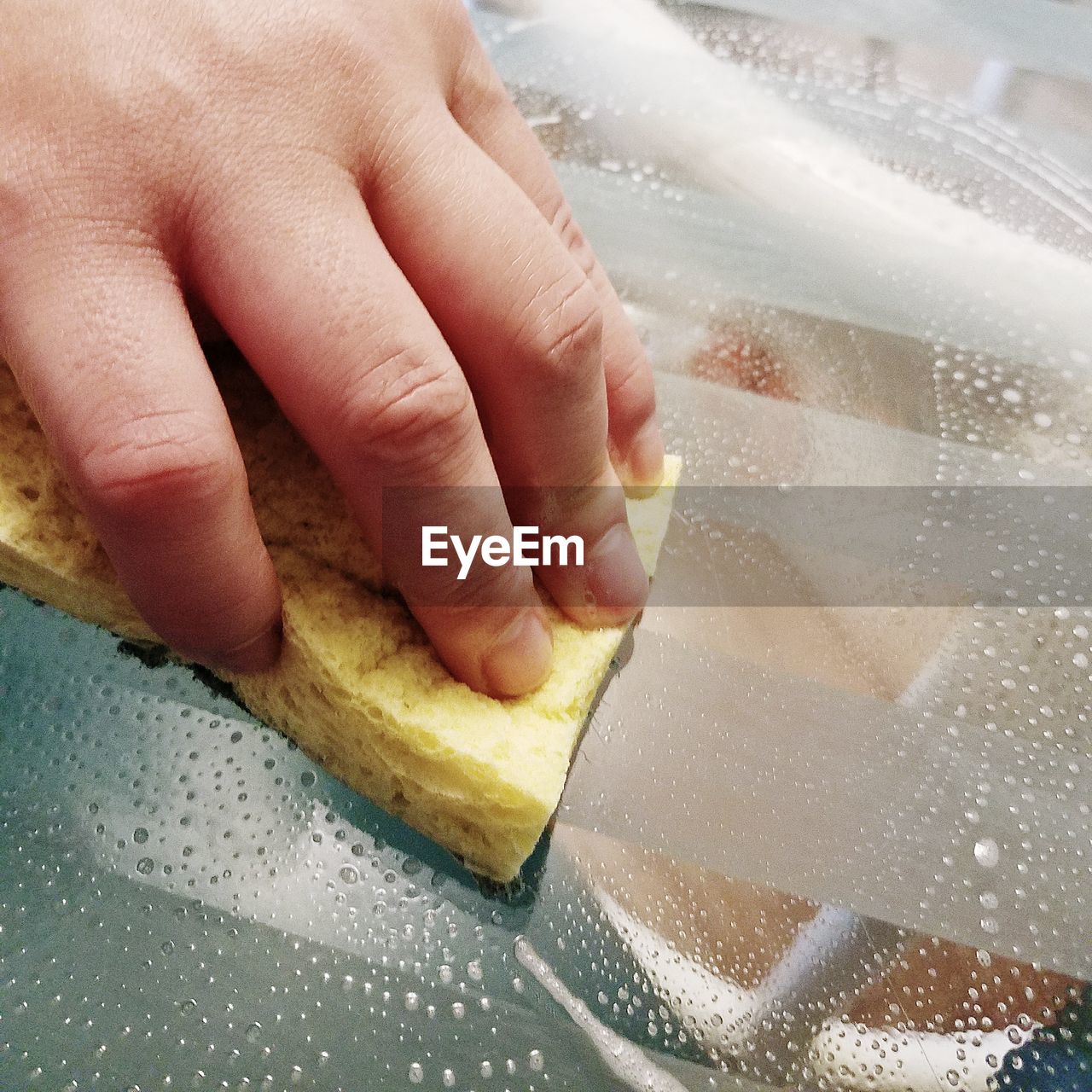 Close-up of hand holding scrubbing with sponge