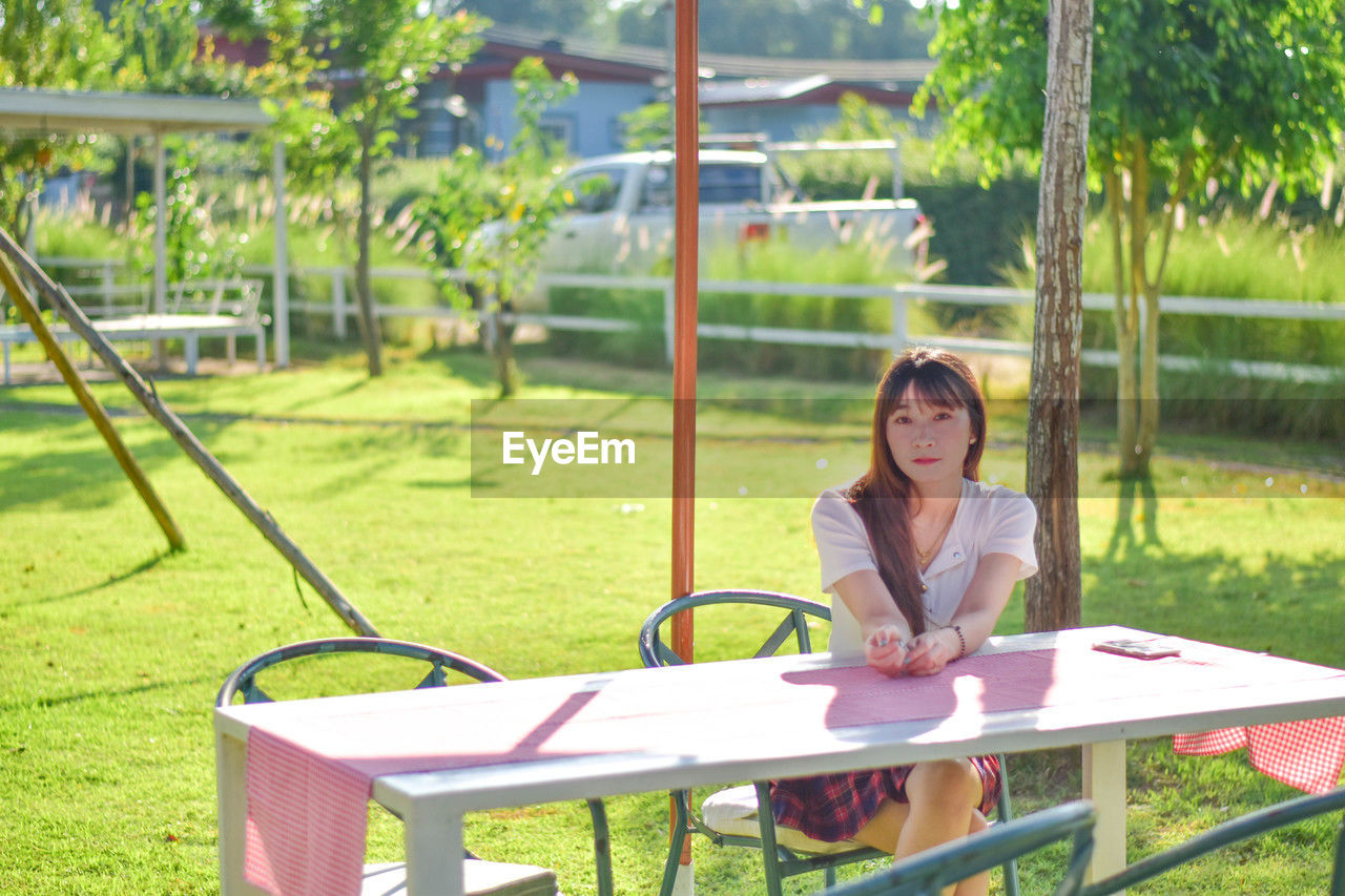 portrait of young woman sitting on swing at park