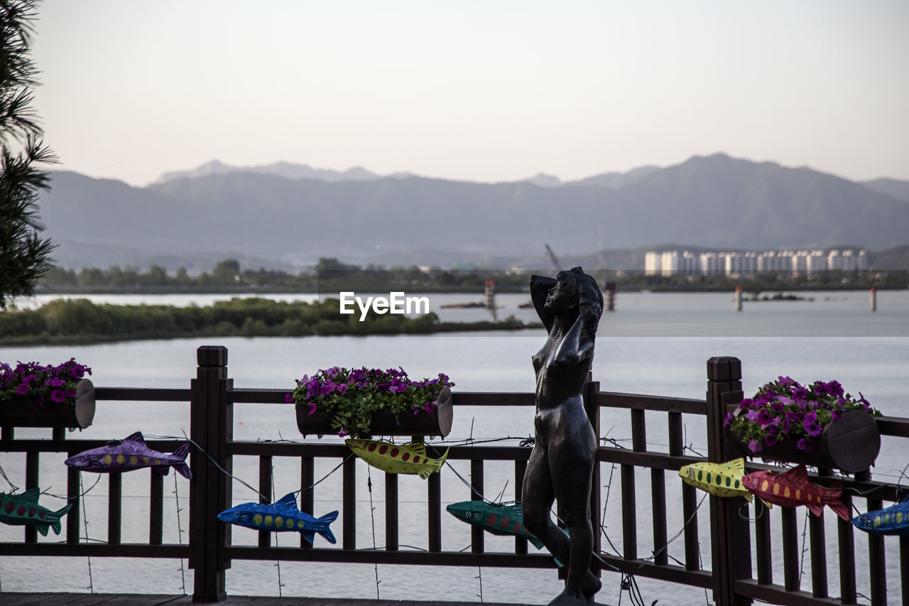 Sculpture by window boxes at railing against lake