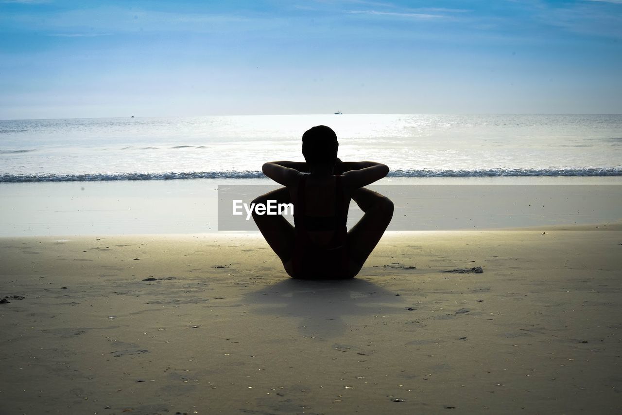 FULL LENGTH OF WOMAN SITTING ON BEACH