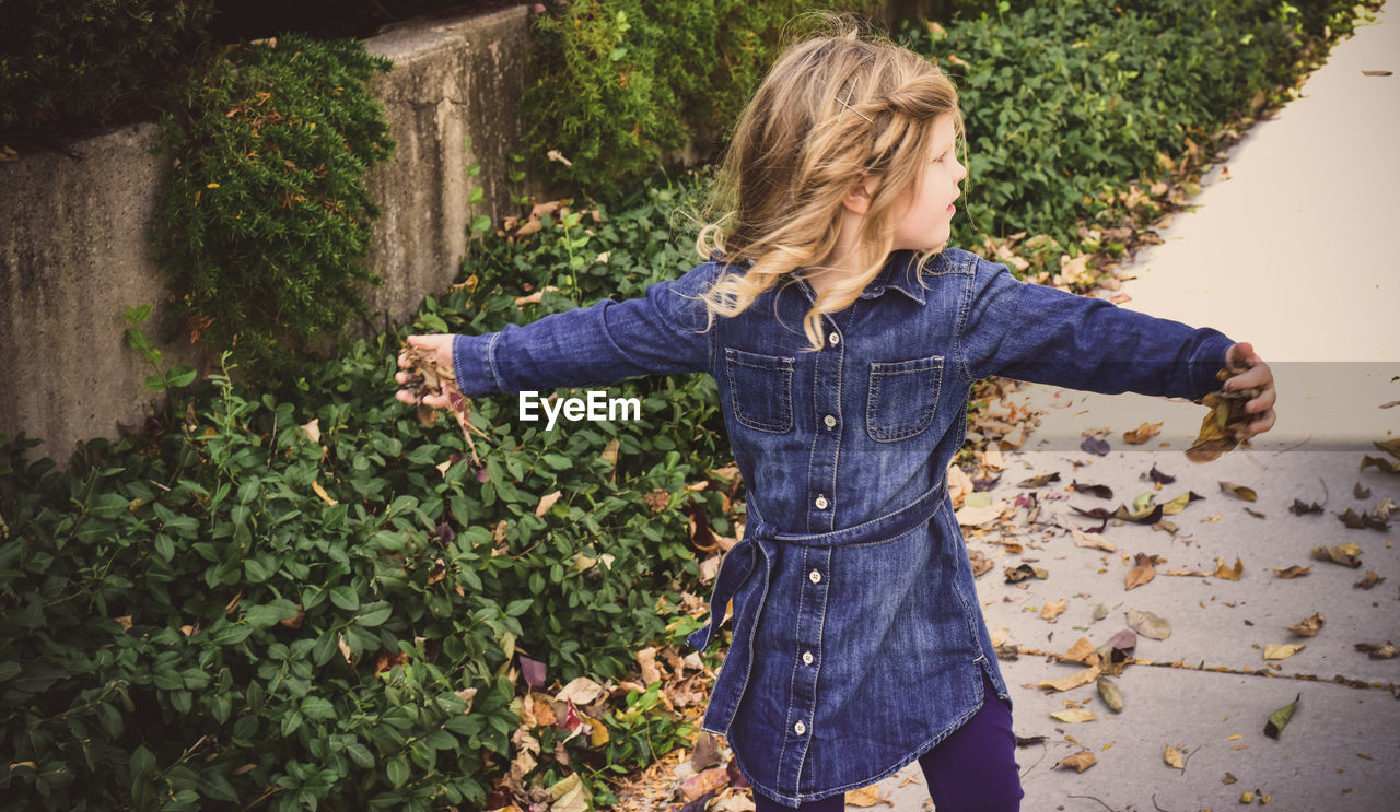 High angle view of girl with arms outstretched standing on footpath