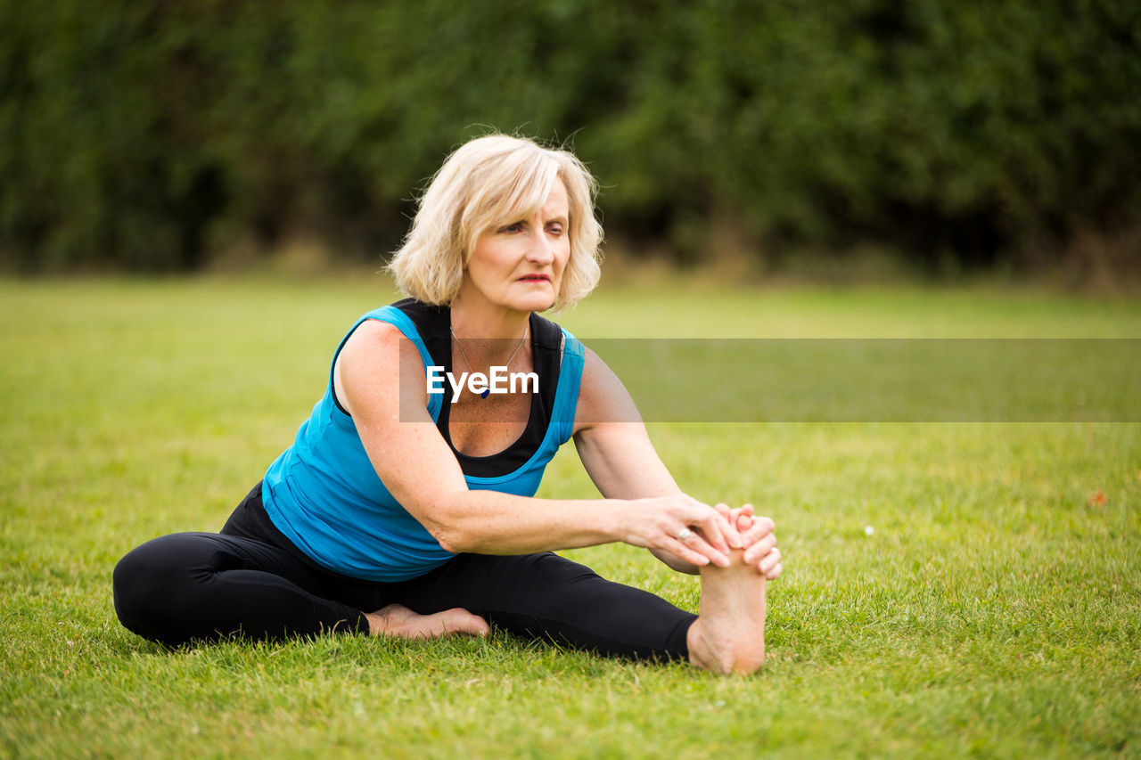YOUNG WOMAN SITTING ON GRASS IN PARK