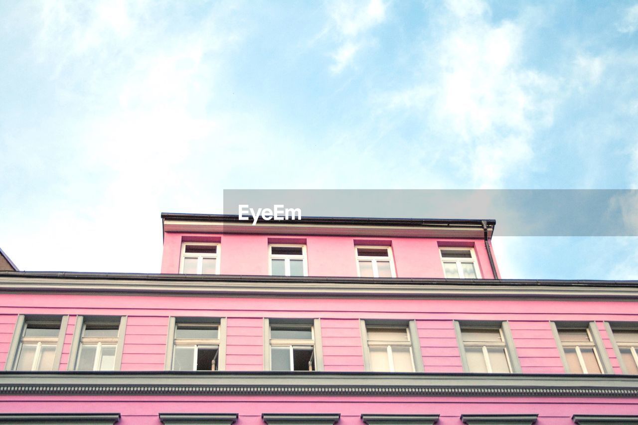 Low angle view of pink building against cloudy sky