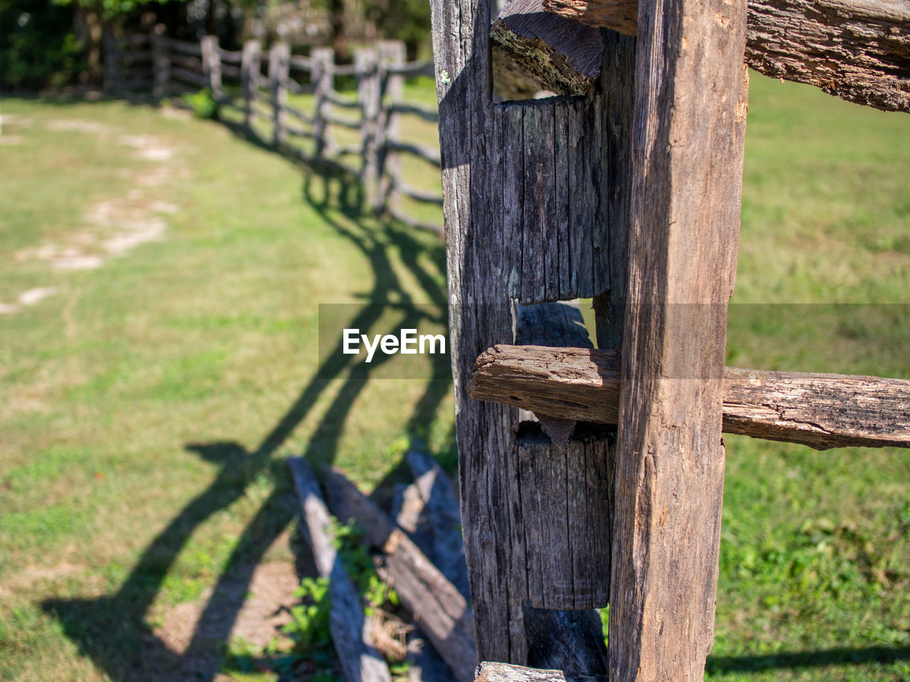 wood, plant, nature, fence, grass, day, no people, green, tree, outdoor structure, sunlight, outdoors, land, landscape, focus on foreground, field, shadow, protection, rural scene, security, wooden post, tree trunk, gate, post, architecture, backyard, agriculture, tranquility, trunk, rural area