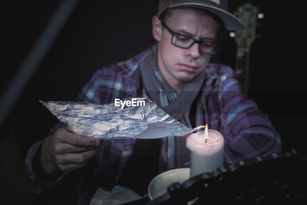 Close-up of young man burning foil on candle
