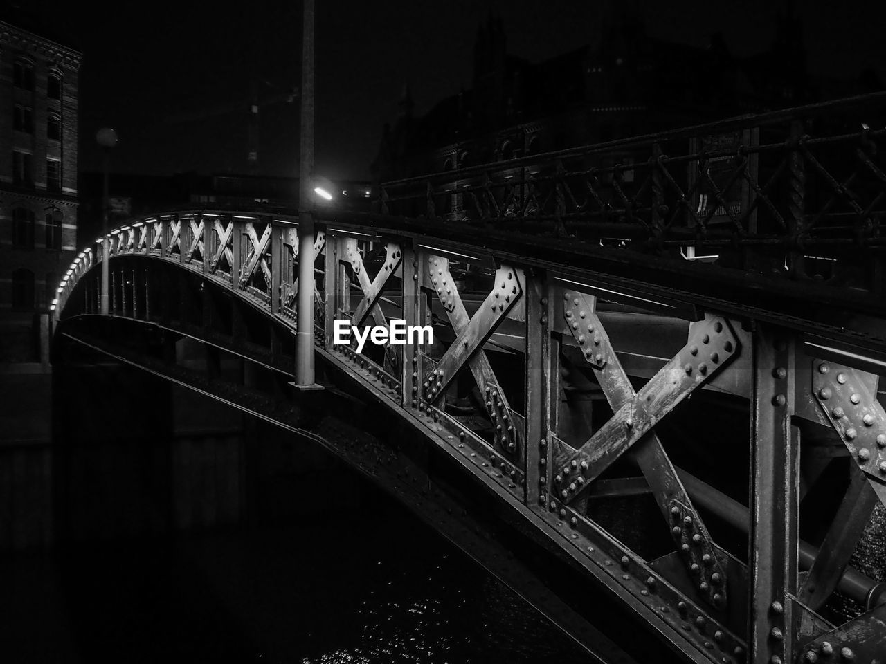 Illuminated footbridge over river at night in city