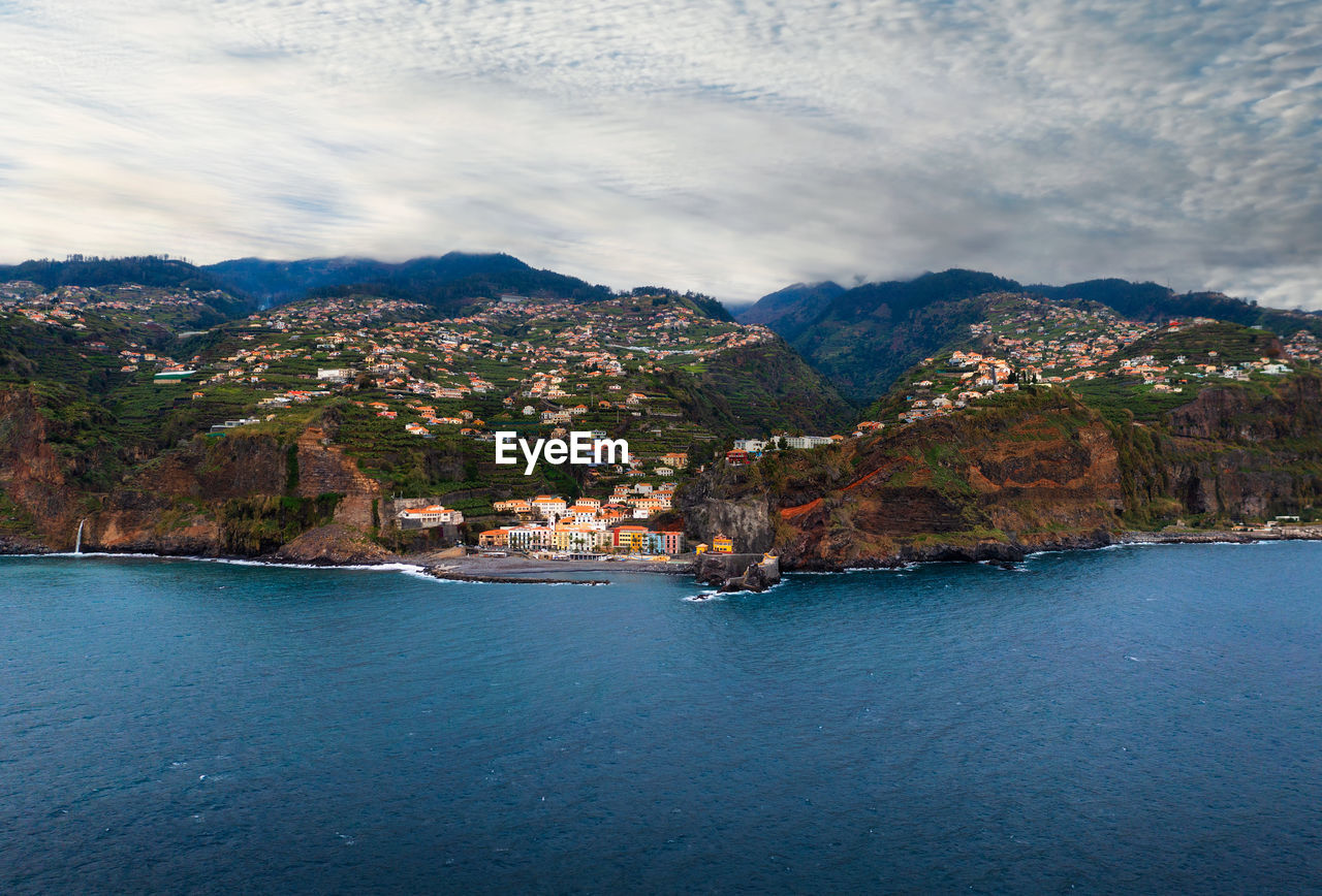 scenic view of sea by mountains against sky