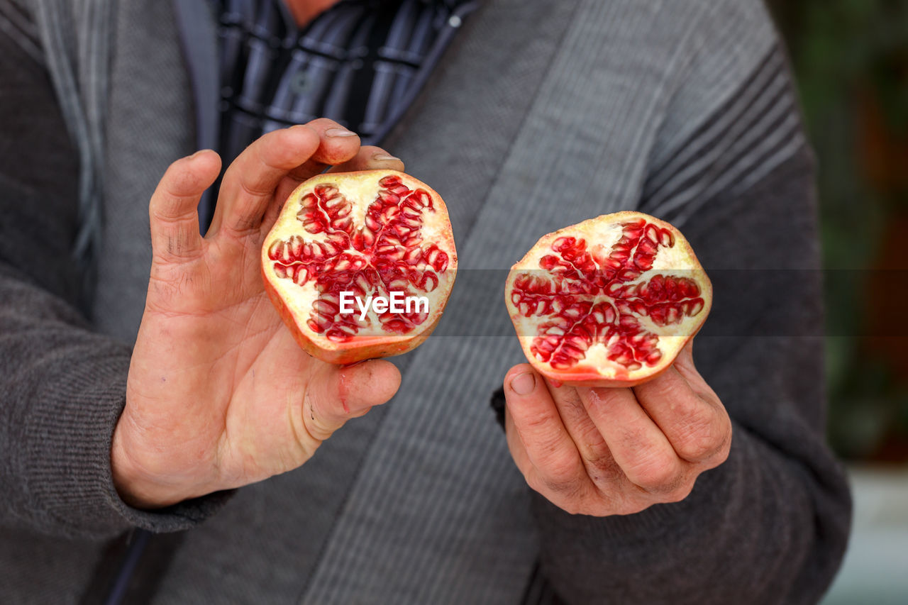  close-up of a hand holding a pomegranate