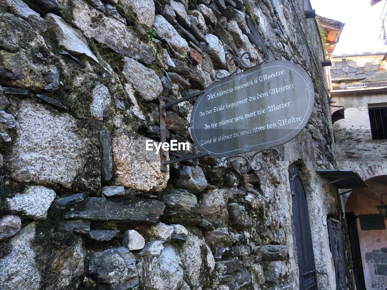 LOW ANGLE VIEW OF TEXT ON ROCK AGAINST BRICK WALL