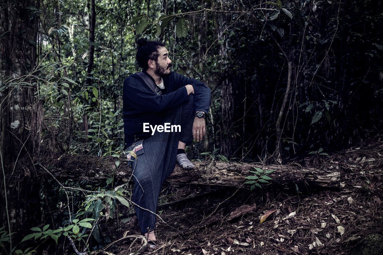 Side view of man looking away in forest