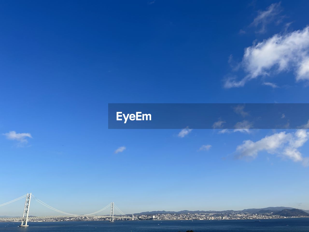 sky, horizon, architecture, bridge, built structure, transportation, travel destinations, sea, water, suspension bridge, blue, travel, cloud, nature, city, dusk, tourism, scenics - nature, bay, bay of water, copy space, no people, landscape, beauty in nature, environment, cityscape, building exterior, outdoors, mountain, ocean, nautical vessel, building, tranquil scene, day, tranquility, sunlight, urban skyline, mode of transportation, beach, clear sky, land, city life, cable-stayed bridge, coast, holiday, morning