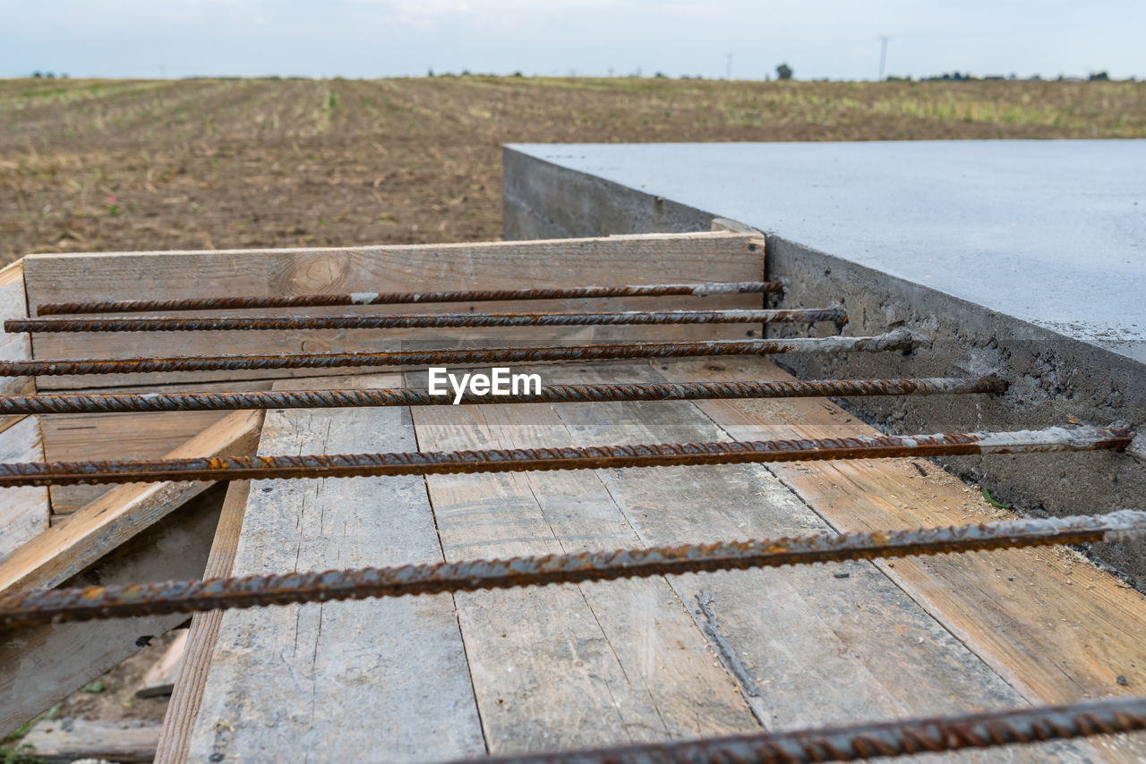 HIGH ANGLE VIEW OF RUSTY METALLIC STRUCTURE ON LAND