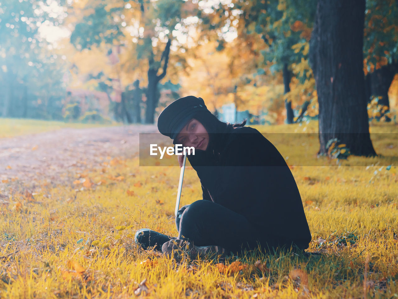 Portrait of young woman with laptop at public park during autumn