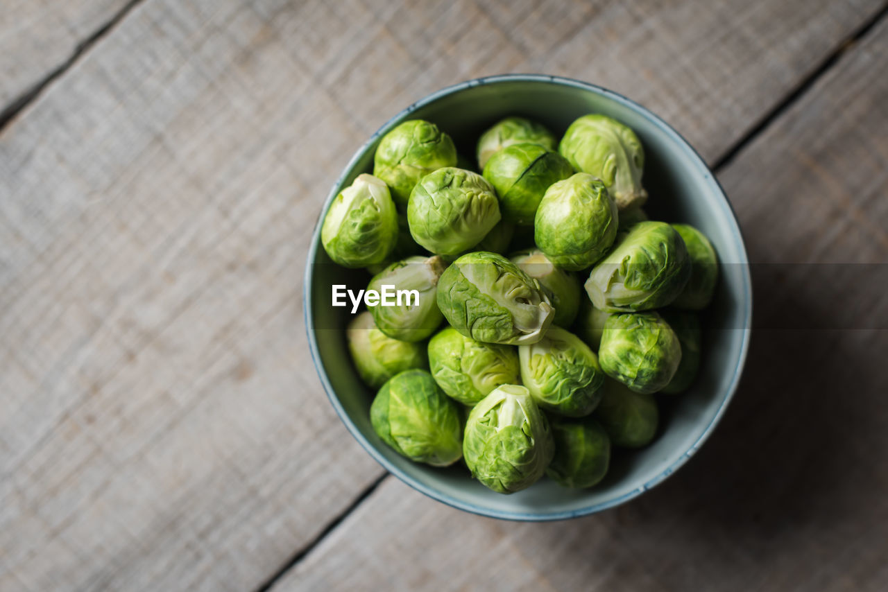 Overhead view of bowl of brussels sprouts on wooden background.