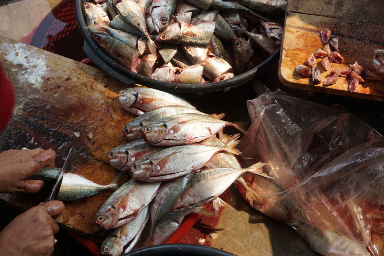 Cropped image of hand chopping fish at market