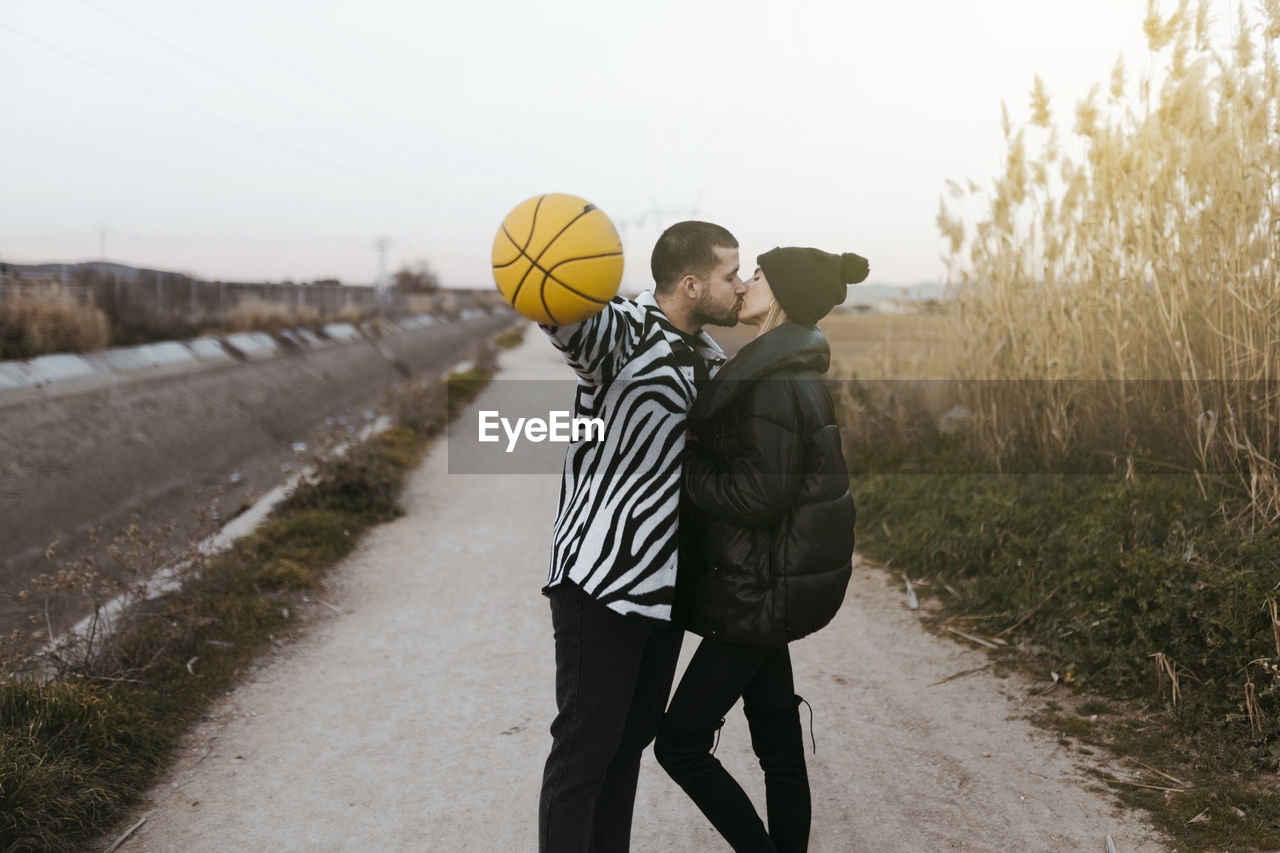 Couple kissing with a yellow basketball in countryside