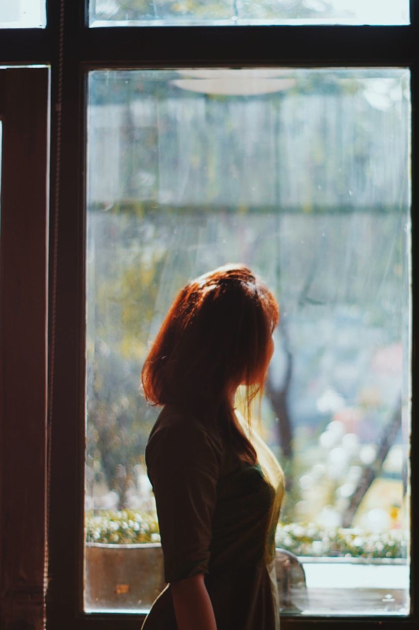 Rear view of woman looking through window