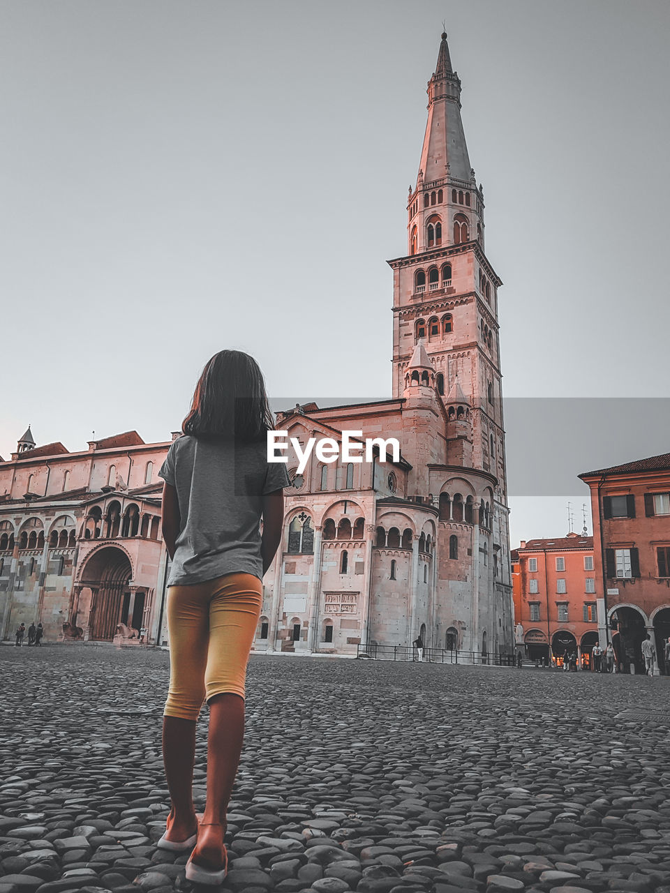 REAR VIEW OF WOMAN STANDING AGAINST BUILDINGS