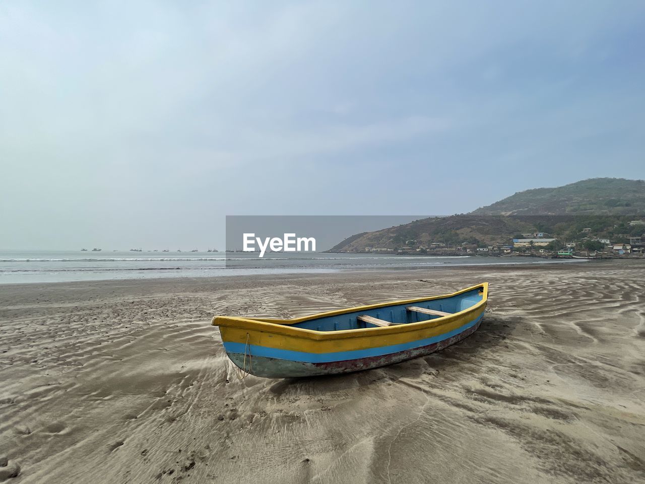 Boat moored on beach against sky