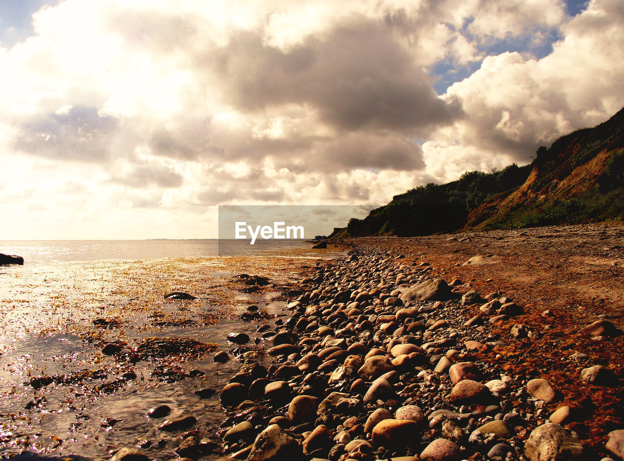 SURFACE LEVEL OF ROCKS ON BEACH AGAINST SKY