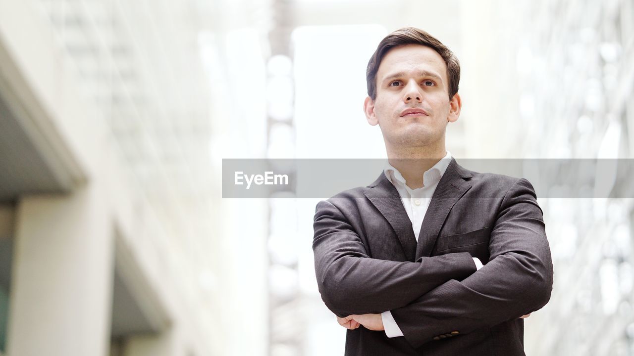 Businessman with arms crossed looking away while standing outdoors