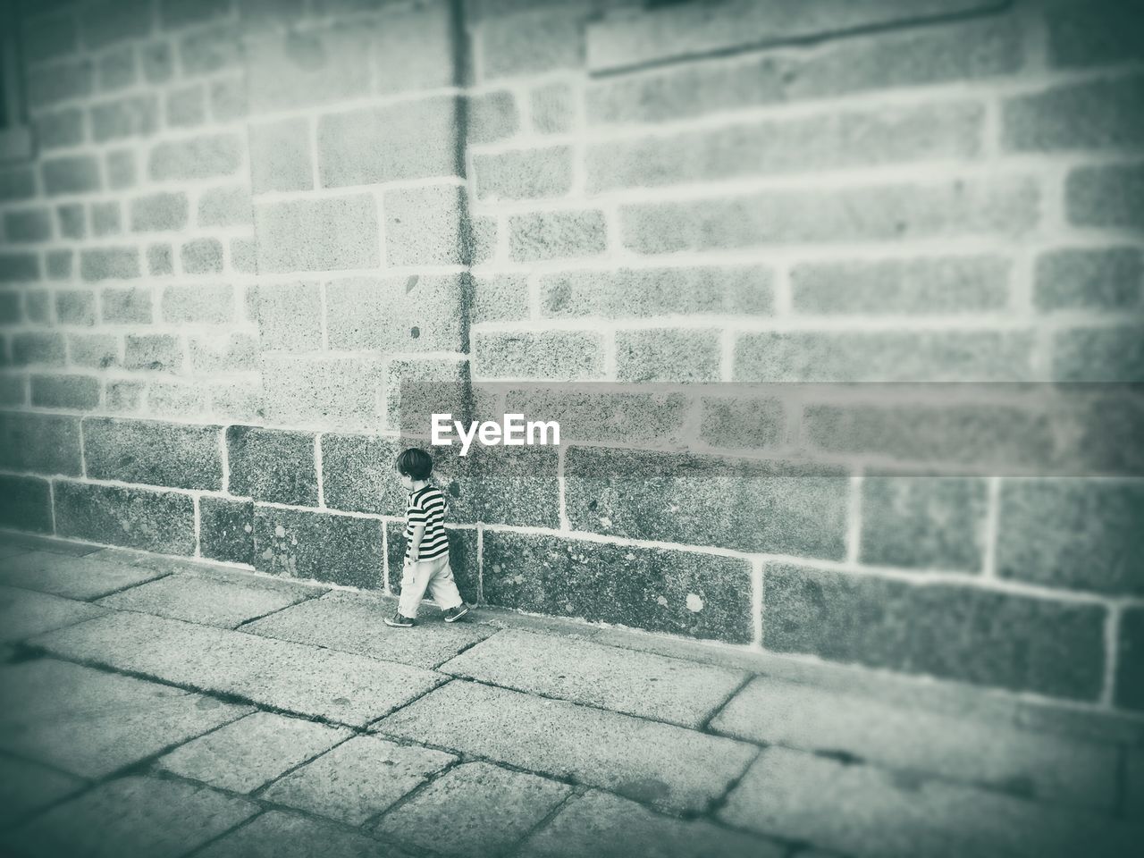 BOY STANDING ON COBBLESTONE