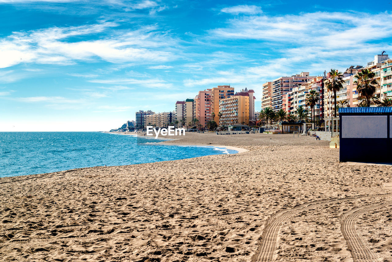 Beach by city against sky