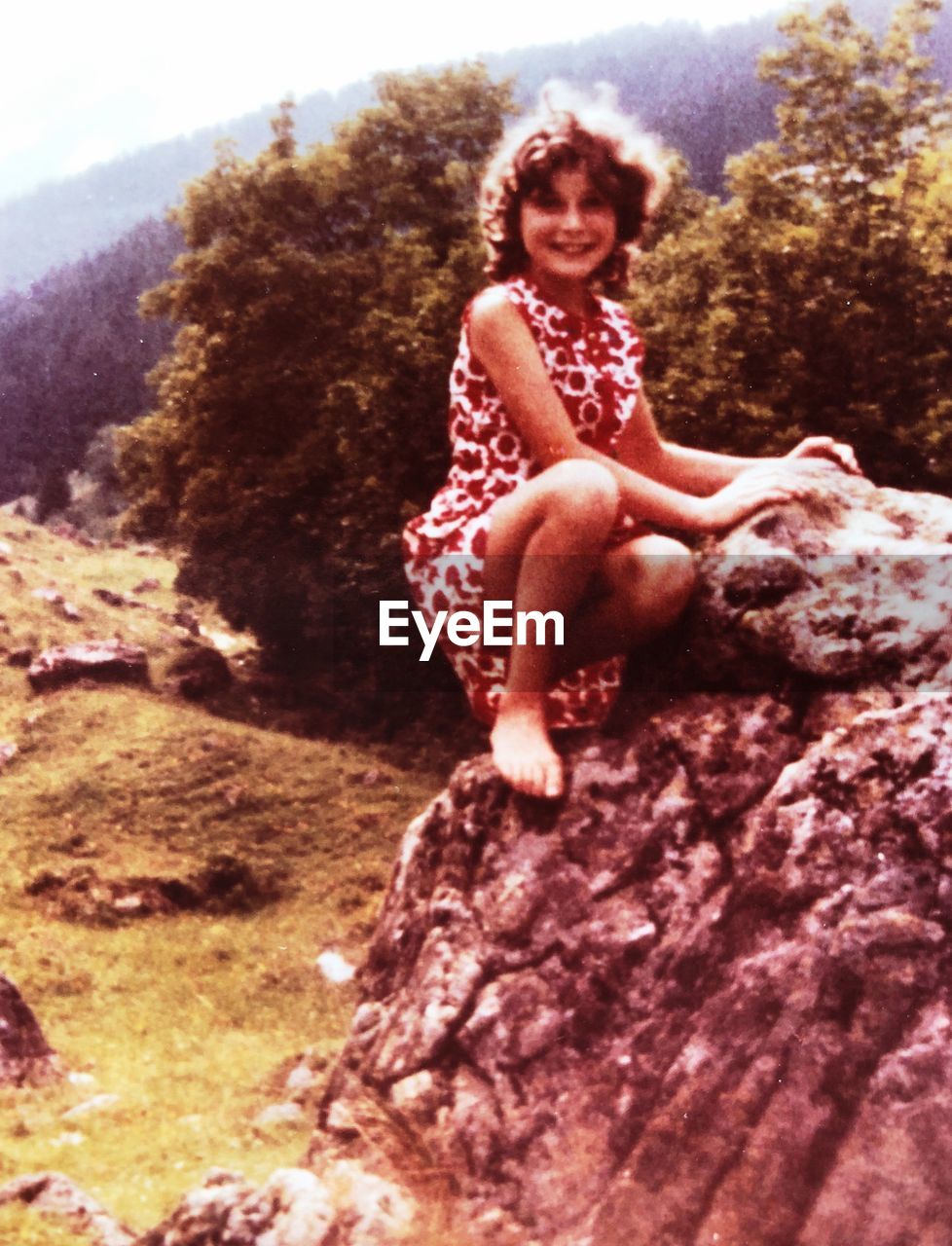 PORTRAIT OF WOMAN SITTING ON ROCK