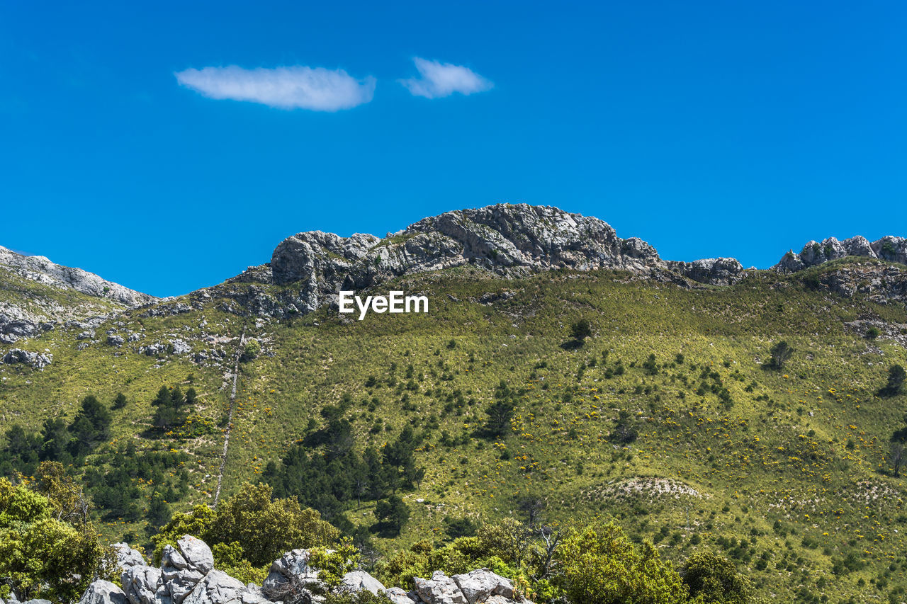 Low angle view of rocks against blue sky