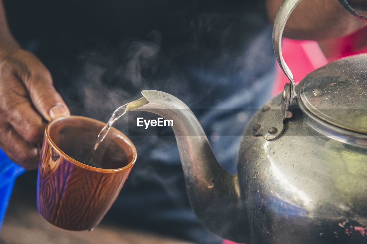 Close-up of hand pouring hot water in cup