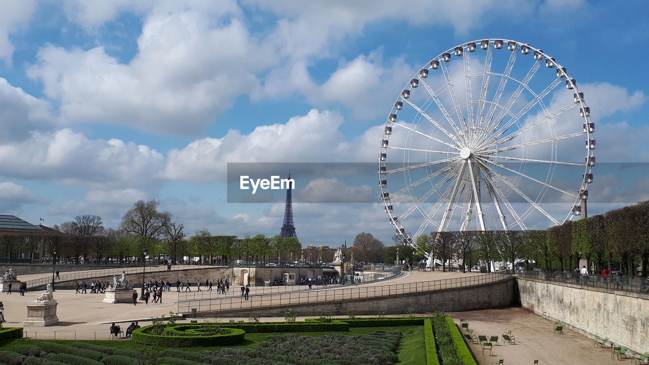 Ferris wheel in city against cloudy sky