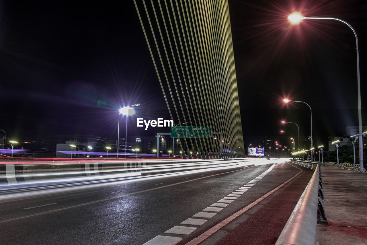 ILLUMINATED LIGHT TRAILS ON ROAD AT NIGHT