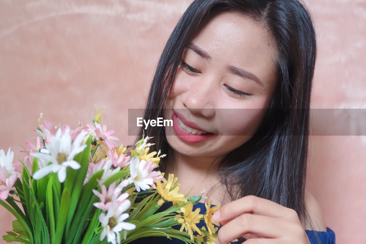 Close-up of smiling young woman with flowers