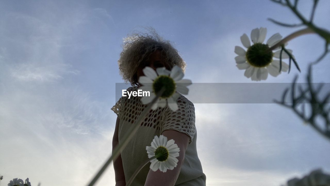 flower, plant, flowering plant, sky, nature, one person, cloud, beauty in nature, freshness, day, adult, low angle view, flower head, spring, fragility, women, outdoors, growth, sunlight, tree, standing, inflorescence, young adult, white