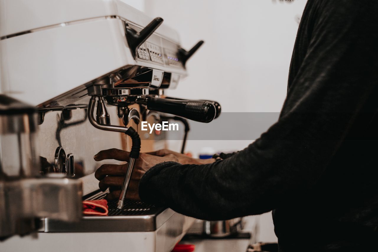 Midsection of man preparing coffee in cafe