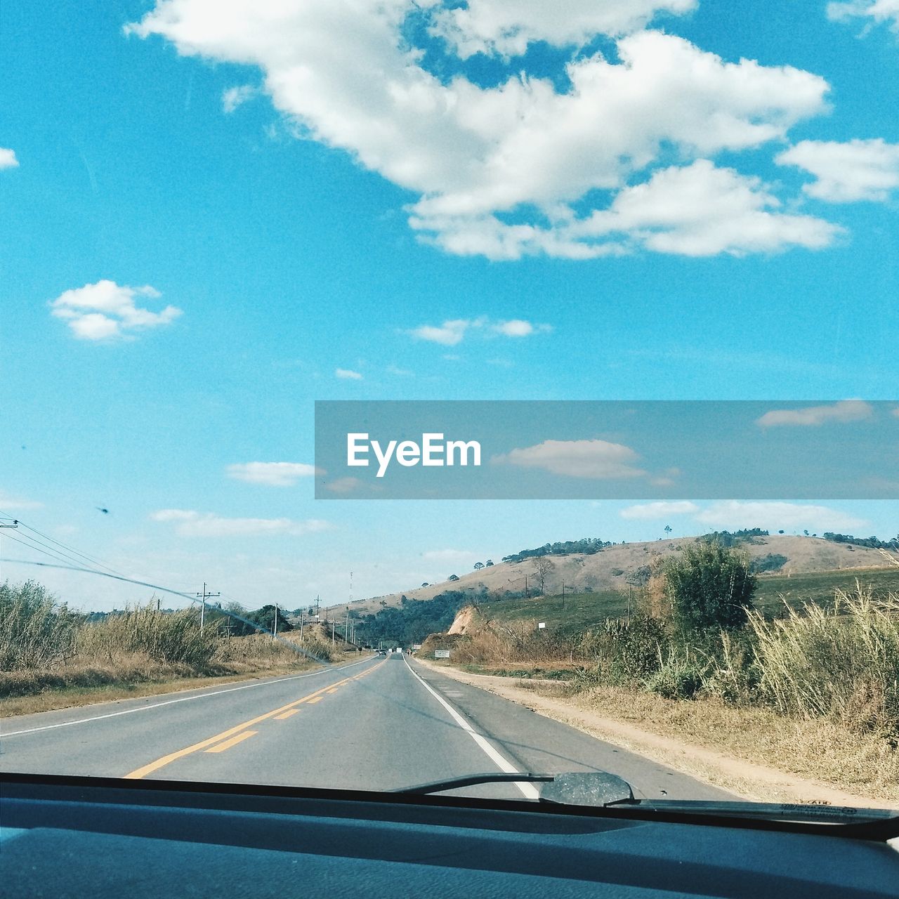 ROAD SEEN THROUGH CAR WINDSHIELD OF SKY