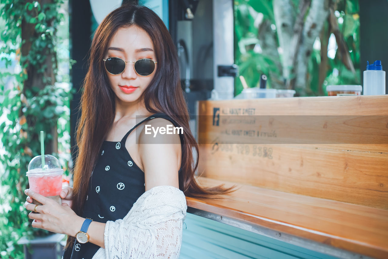 Young woman holding drink standing outdoors