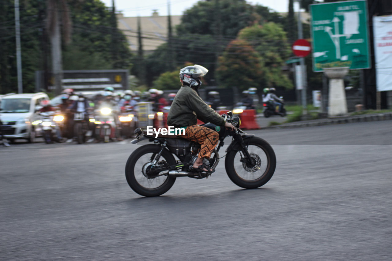 MAN RIDING MOTORCYCLE ON ROAD