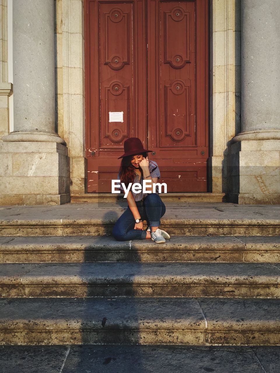 FULL LENGTH OF WOMAN SITTING ON STAIRCASE AT ENTRANCE