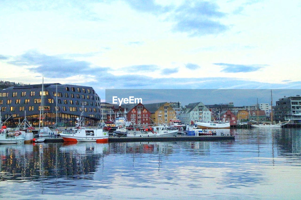 BOATS MOORED AT HARBOR BY RIVER AGAINST SKY