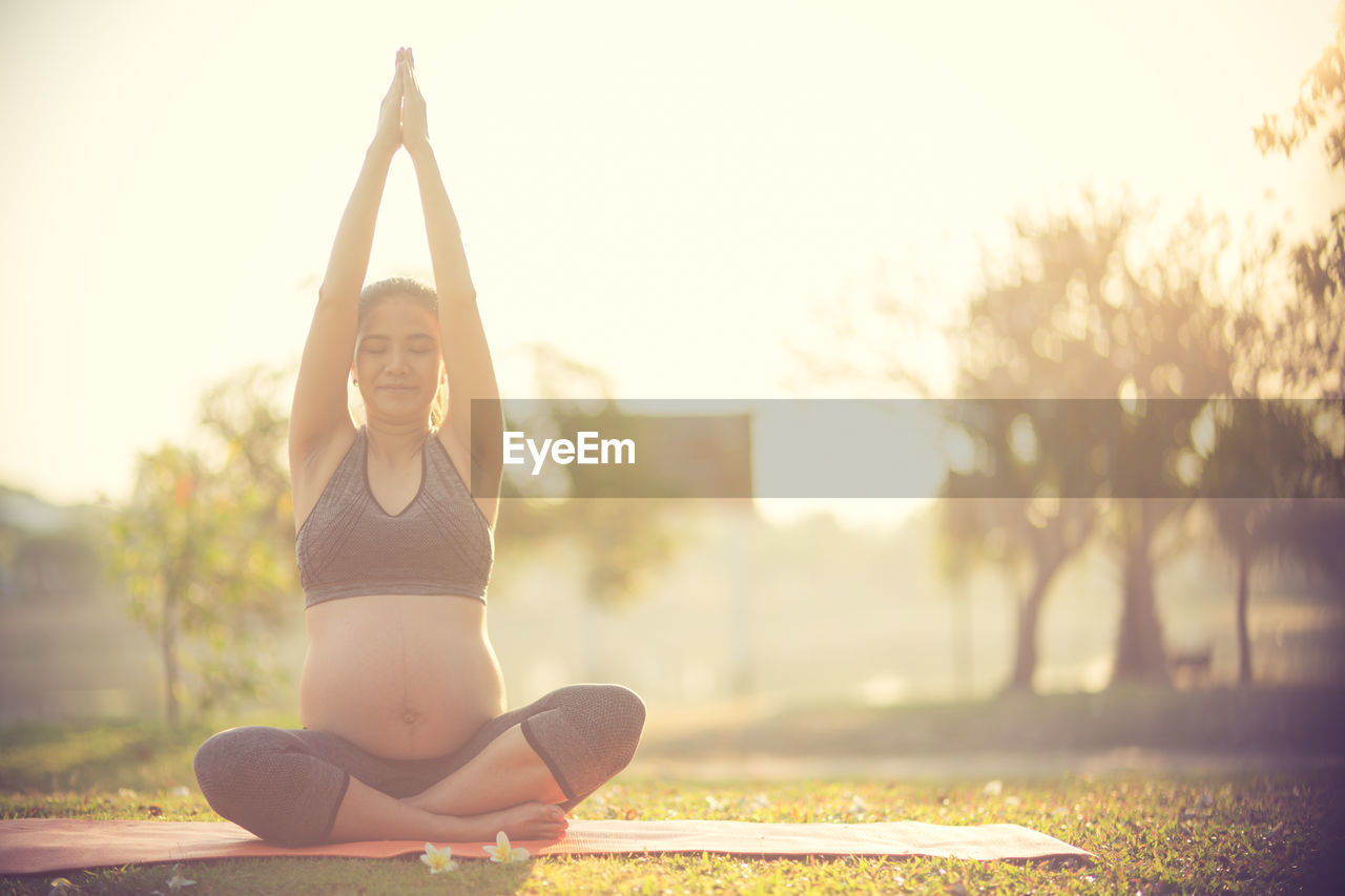 Pregnant woman doing yoga on field
