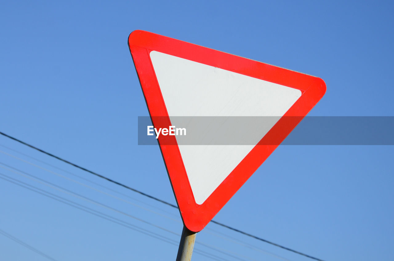 Low angle view of road sign against clear blue sky