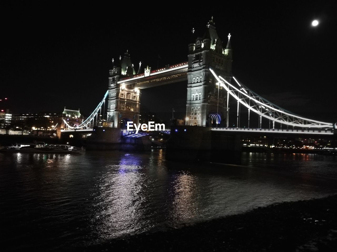 ILLUMINATED BRIDGE OVER RIVER AGAINST SKY AT NIGHT