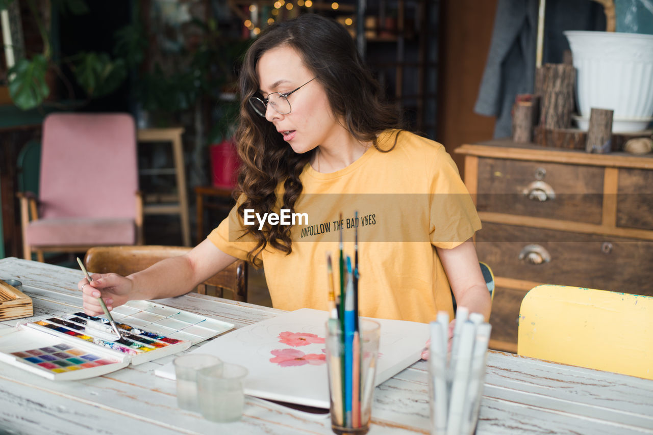 YOUNG WOMAN LOOKING AWAY WHILE TABLE